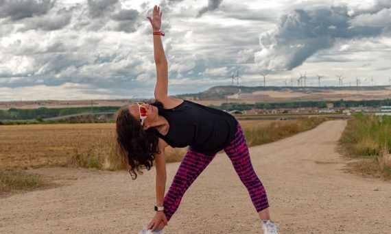 Outdoor fitness scene of a woman stretching on a dirt path in Soto de Cerrato amidst scenic landscapes.